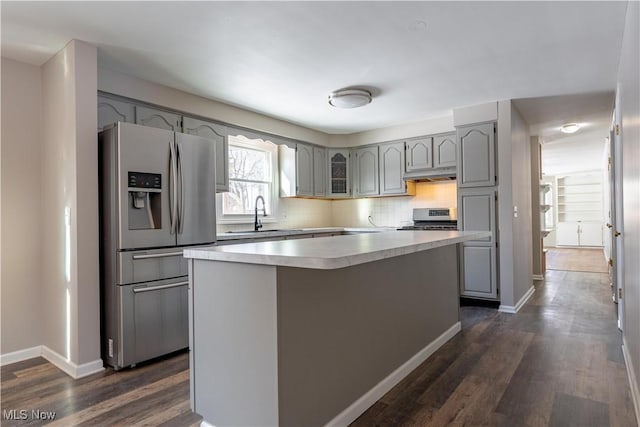 kitchen with stainless steel appliances, sink, tasteful backsplash, gray cabinets, and a kitchen island