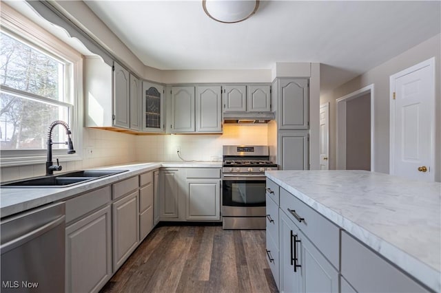 kitchen featuring dark wood-type flooring, gray cabinets, backsplash, appliances with stainless steel finishes, and sink