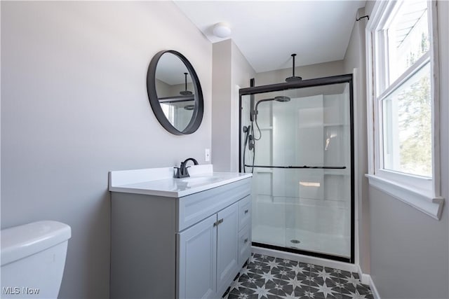 bathroom featuring toilet, vanity, and a shower with shower door