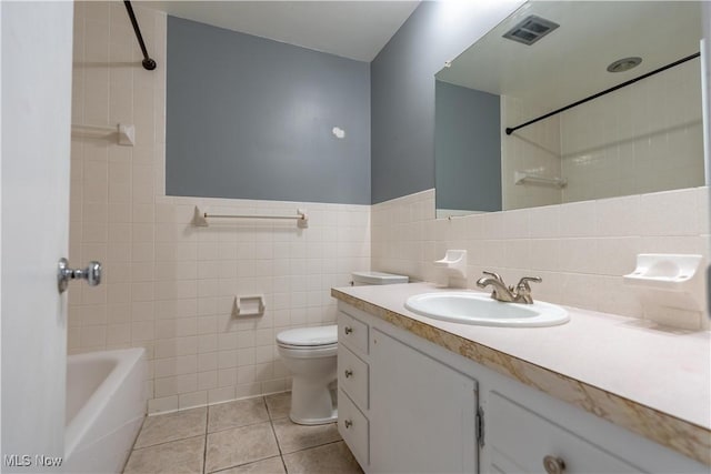 full bathroom featuring tile patterned flooring, tile walls, toilet, vanity, and tiled shower / bath combo