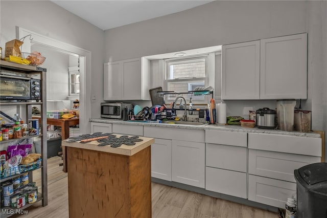 kitchen featuring white cabinets, light hardwood / wood-style flooring, and sink