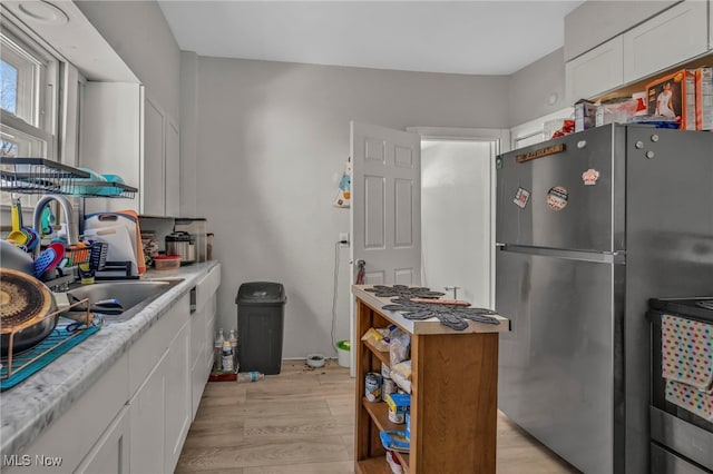 kitchen featuring sink, stainless steel appliances, white cabinetry, and light hardwood / wood-style floors