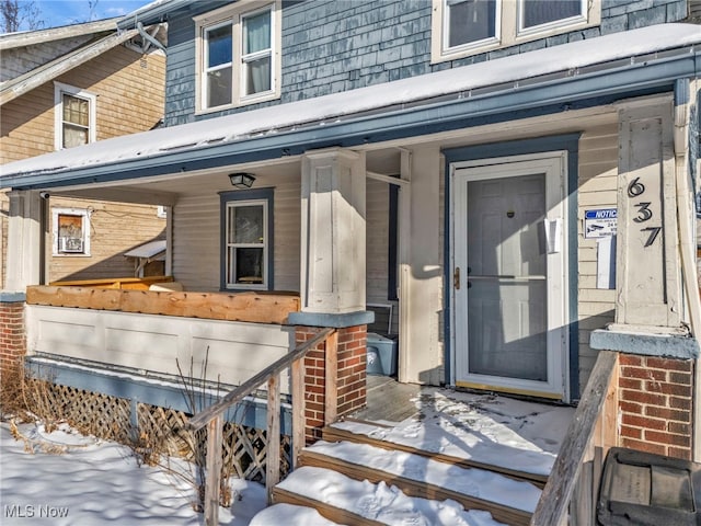 snow covered property entrance featuring a porch