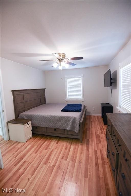 bedroom with ceiling fan, light wood-type flooring, and multiple windows