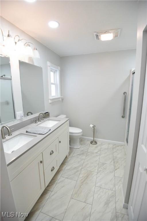 bathroom with toilet, vanity, and a shower with door