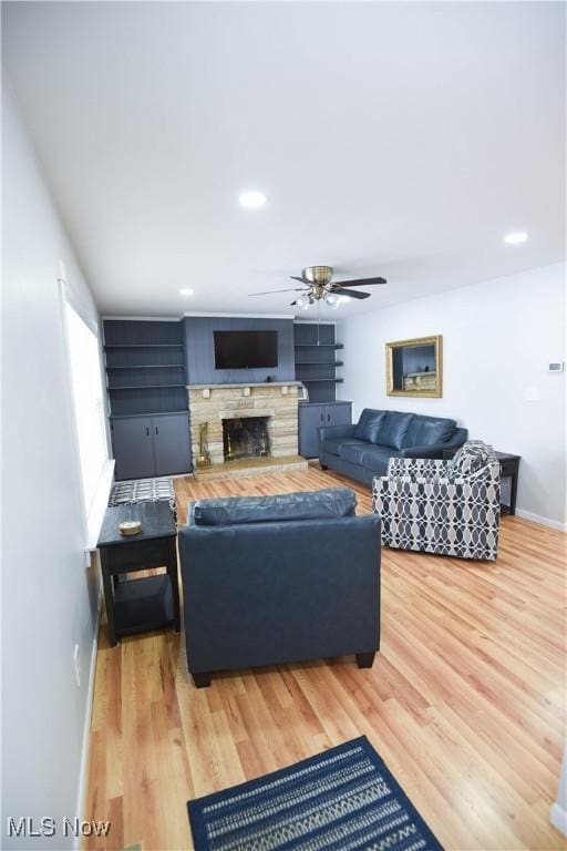 living room featuring ceiling fan, a fireplace, and hardwood / wood-style floors