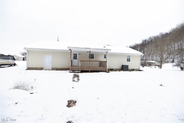 snow covered house with a deck and central AC