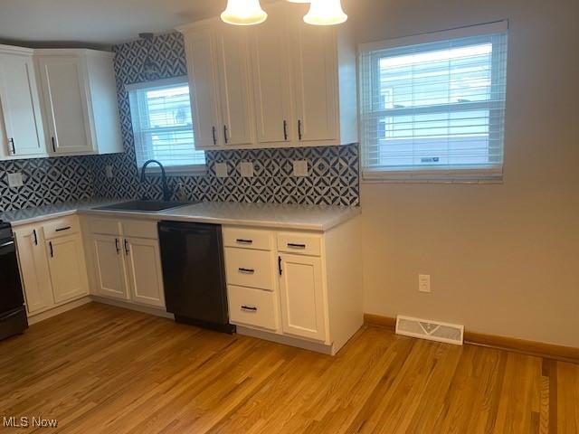 kitchen with sink, white cabinetry, dishwasher, and light wood-type flooring