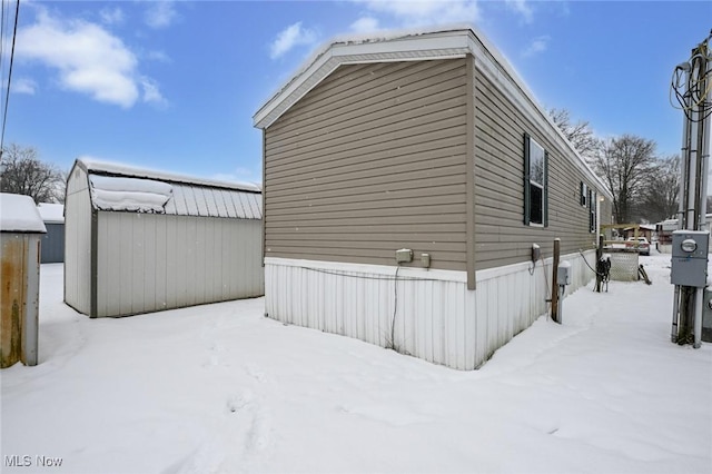 view of snow covered exterior with a storage unit