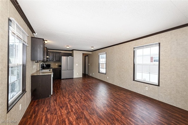 kitchen featuring dark hardwood / wood-style flooring, dark brown cabinetry, crown molding, and stainless steel fridge