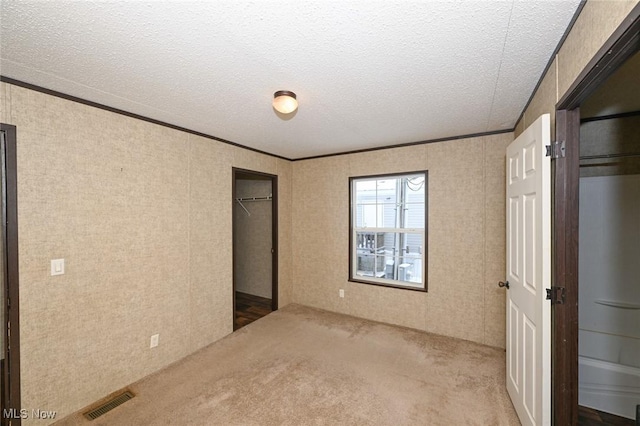 unfurnished bedroom with carpet flooring, a textured ceiling, and ornamental molding