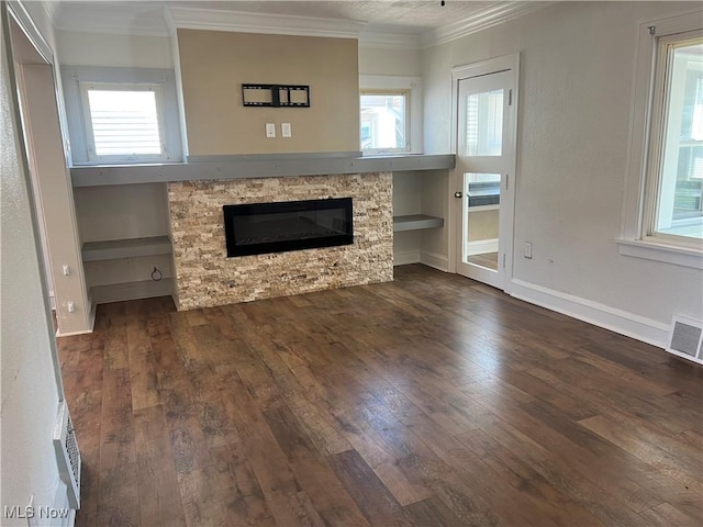 unfurnished living room featuring dark hardwood / wood-style floors, ornamental molding, and a stone fireplace