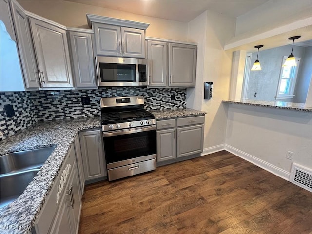 kitchen with stone countertops, appliances with stainless steel finishes, gray cabinets, and tasteful backsplash