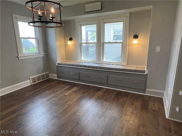 unfurnished dining area featuring a notable chandelier, ornamental molding, and dark hardwood / wood-style floors