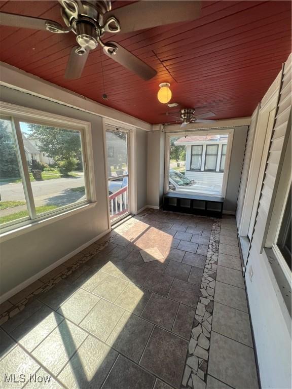 unfurnished sunroom featuring wooden ceiling and ceiling fan