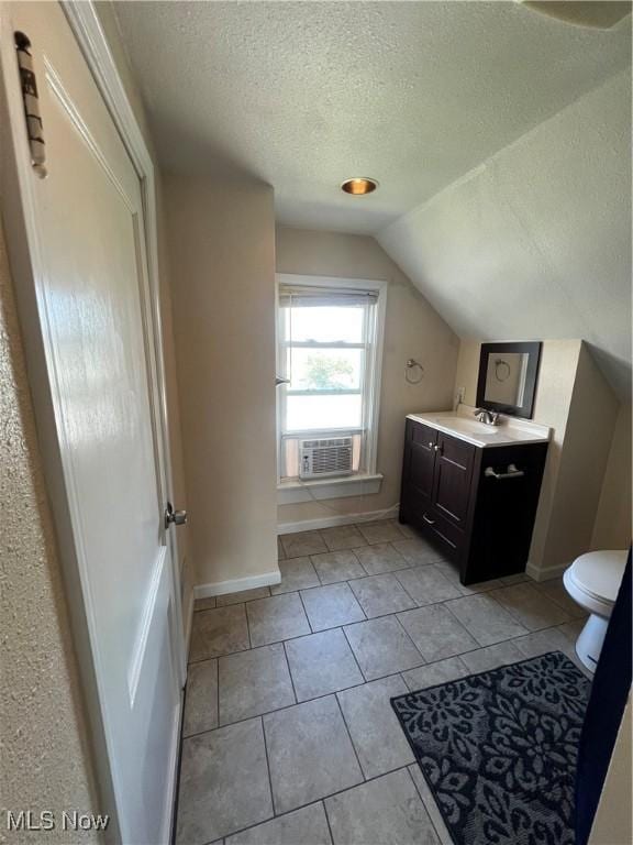 bathroom with toilet, lofted ceiling, tile patterned floors, a textured ceiling, and vanity