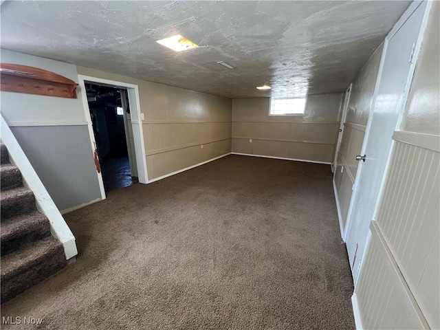 basement with a textured ceiling and dark colored carpet