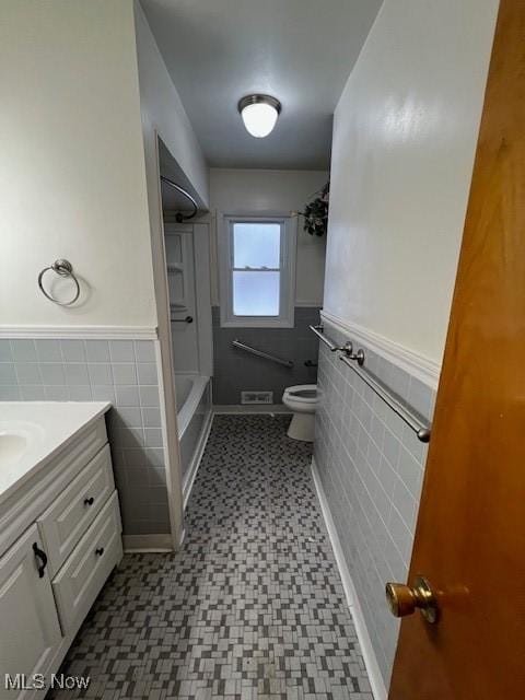 full bathroom featuring toilet, vanity, tile walls, and shower / bathing tub combination