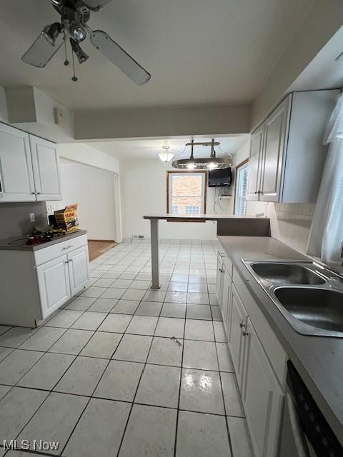 kitchen featuring white cabinets, light tile patterned flooring, sink, and dishwashing machine