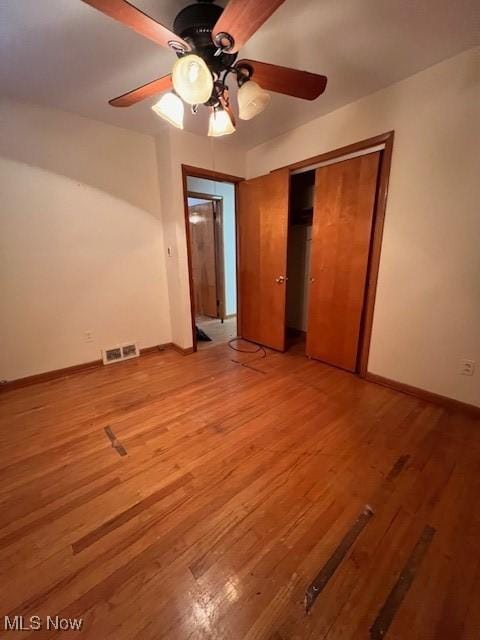 unfurnished bedroom featuring ceiling fan, light hardwood / wood-style floors, and a closet