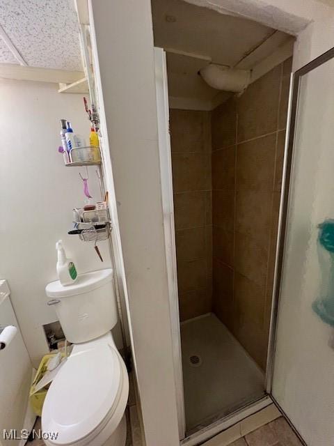 bathroom featuring toilet, an enclosed shower, and tile patterned floors