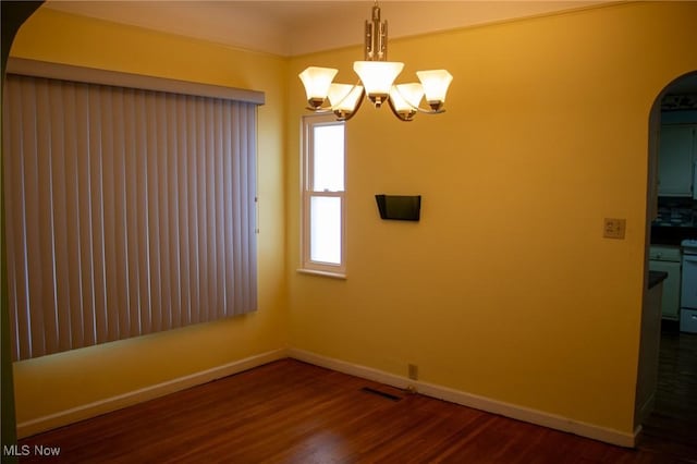 empty room featuring dark wood-type flooring and a chandelier