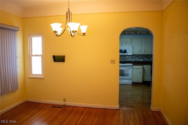 unfurnished dining area with dark hardwood / wood-style flooring and a chandelier