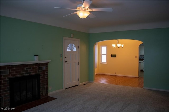 carpeted entrance foyer featuring ceiling fan with notable chandelier and a fireplace