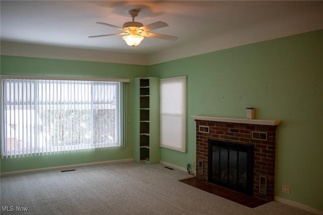 unfurnished living room featuring a brick fireplace, ceiling fan, and carpet