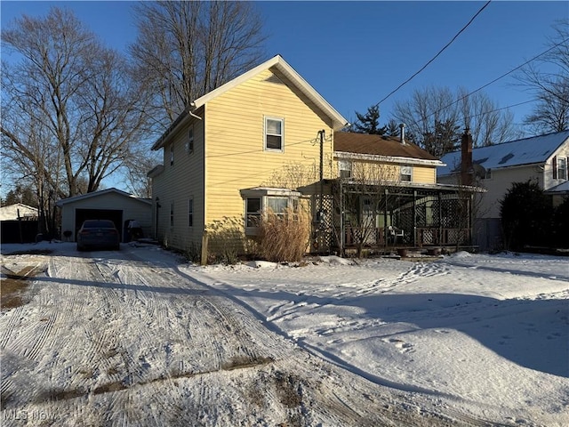 view of snowy exterior with a garage and an outbuilding