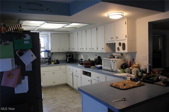 kitchen featuring black fridge, white cabinetry, and kitchen peninsula