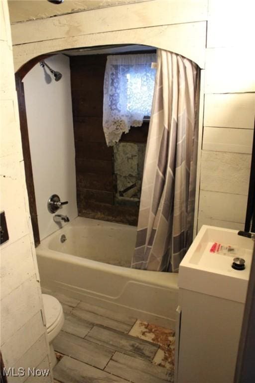 bathroom featuring shower / bathtub combination with curtain, wood walls, and toilet