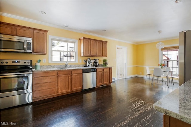 kitchen with stainless steel appliances, light stone countertops, pendant lighting, and sink