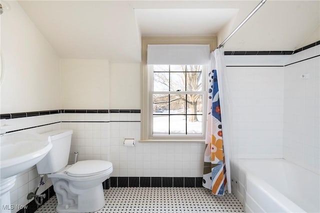 bathroom with toilet, shower / bath combo, and tile walls