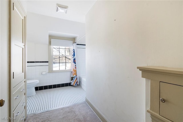 bathroom featuring toilet, tile walls, and shower / bathtub combination with curtain