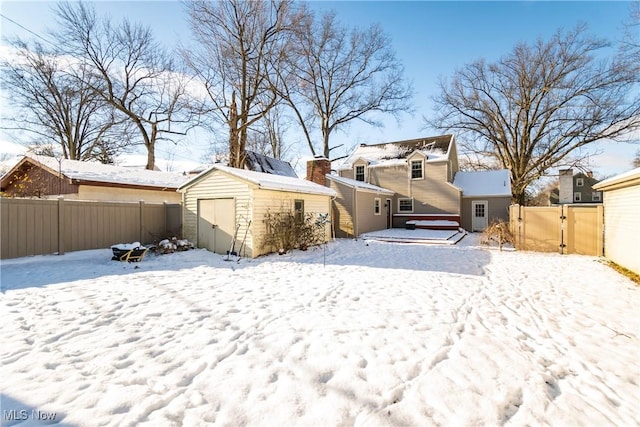 snow covered rear of property with a shed