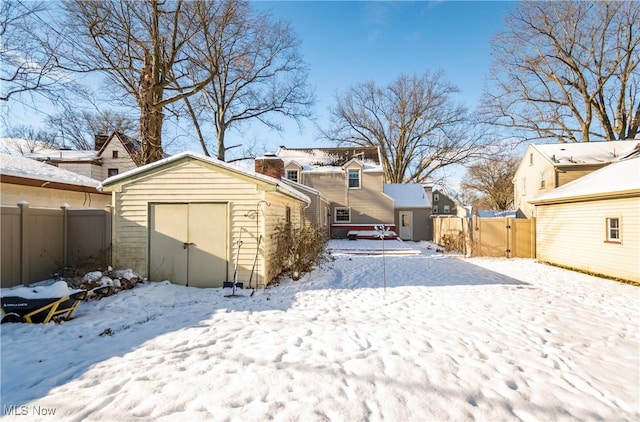 snow covered rear of property with a storage shed