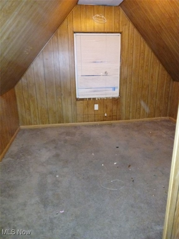 bonus room featuring carpet floors, vaulted ceiling, and wood walls