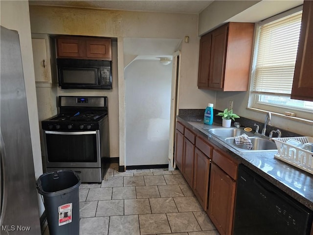 kitchen with brown cabinetry, a sink, and black appliances
