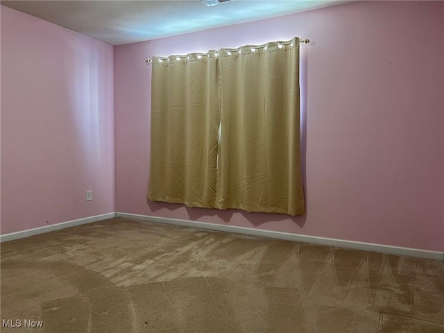 empty room with carpet, visible vents, and baseboards