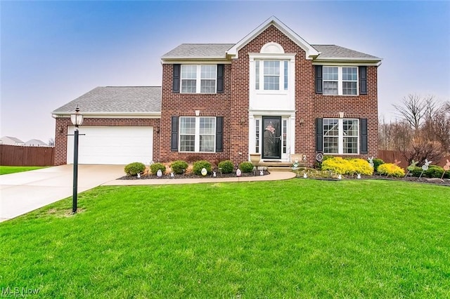 colonial-style house featuring brick siding, an attached garage, a front yard, fence, and driveway