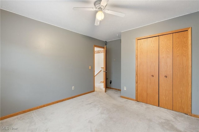 unfurnished bedroom featuring light colored carpet, ceiling fan, and a closet