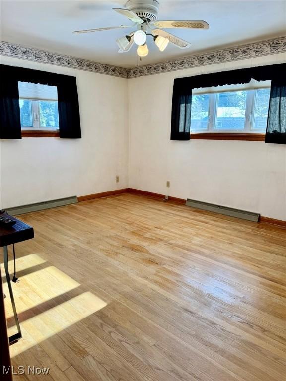 empty room featuring a baseboard radiator, ceiling fan, and light hardwood / wood-style floors