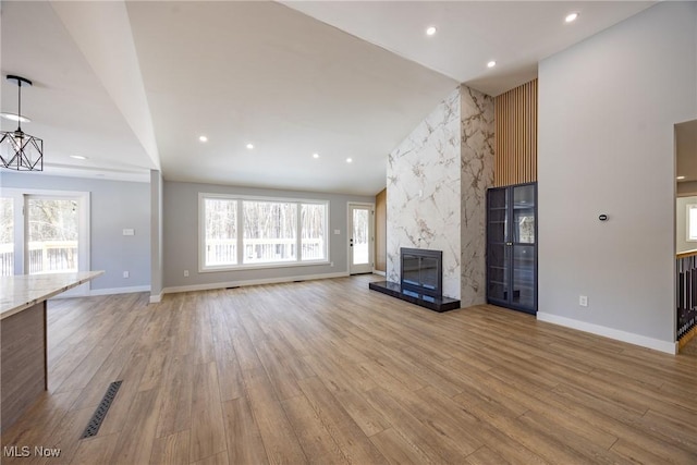 unfurnished living room with light hardwood / wood-style flooring, vaulted ceiling, and a fireplace