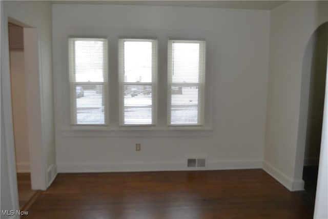 empty room featuring plenty of natural light and dark hardwood / wood-style floors