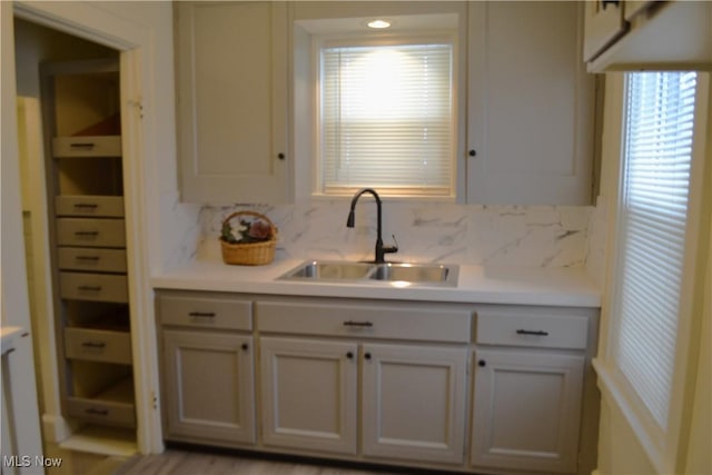 kitchen with white cabinetry, backsplash, and sink