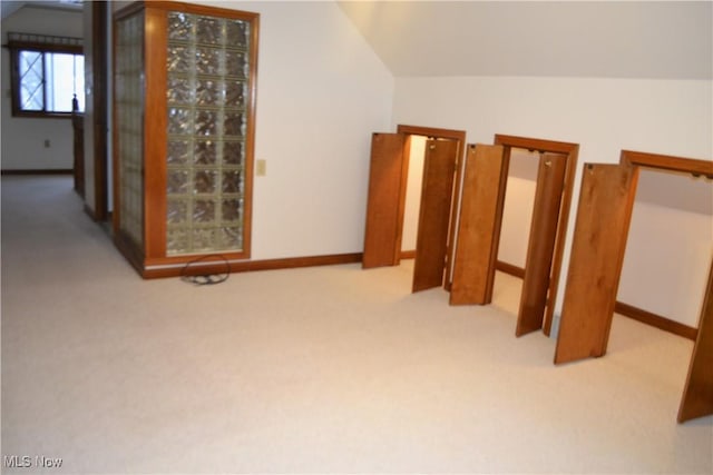 additional living space featuring vaulted ceiling and light carpet