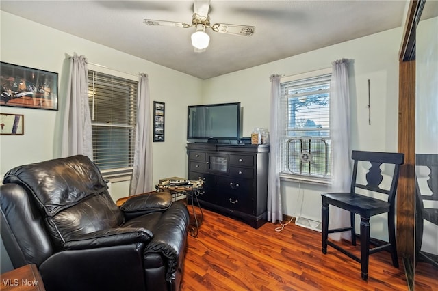 sitting room with dark wood-type flooring and ceiling fan