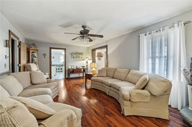 living room with ceiling fan and dark wood-type flooring