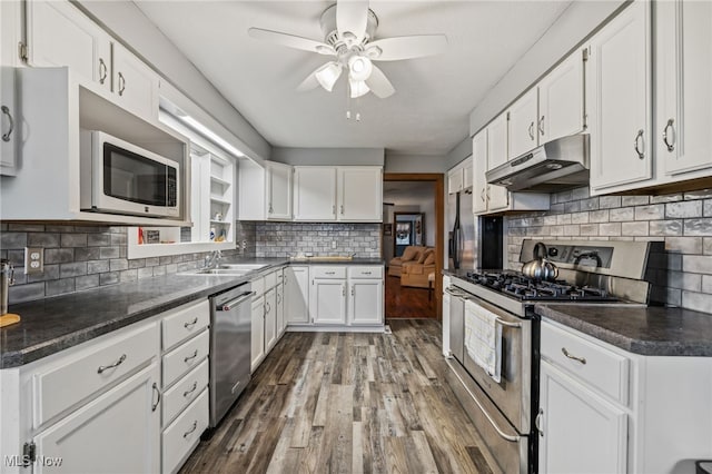 kitchen with dark wood-type flooring, stainless steel appliances, backsplash, white cabinetry, and ceiling fan